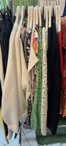 Auswahl an farbenfrohen und gemusterten Oberteilen auf einem Kleiderständer in einem Modegeschäft.