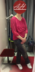 Eine Kundin in ihrer bisherigen Kleidung während einer persönlichen Shoppingtour mit Stilberatung, aufgenommen in einer Boutique-Umkleide