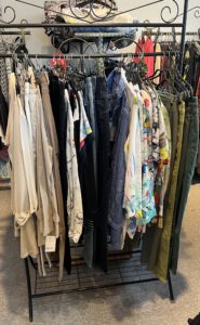 Kleiderständer mit gemischter Auswahl an Hosen und Oberteilen im zweiten Geschäft während einer Shoppingtour mit Stilberatung.