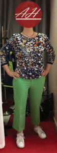 Eine Kundin in einem floral gemusterten Oberteil und grüner Hose während einer Shoppingtour mit Stilberatung.