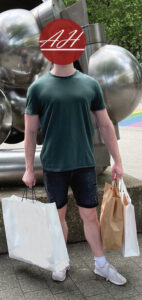 Ein männlicher Kunde nach einer Shoppingtour mit Stilberatung, stehend im Freien mit mehreren Einkaufstaschen